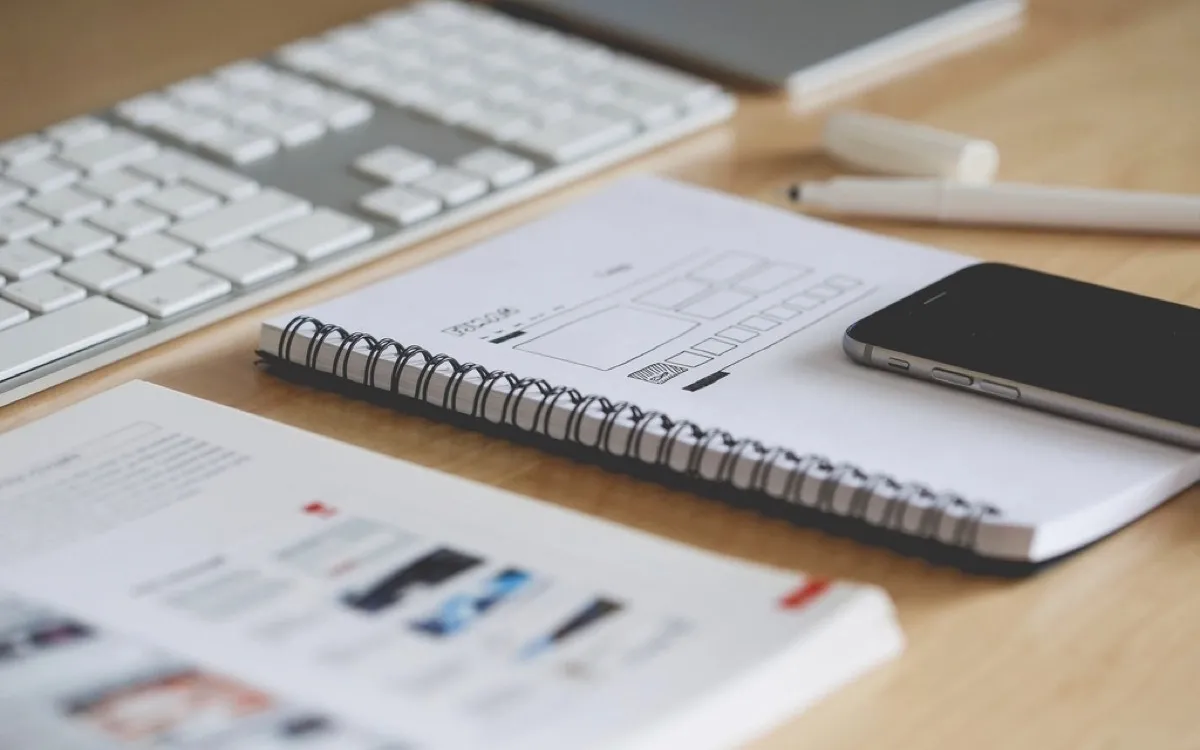 A desk with a keyboard, a phone, a notebook and printed analytics charts