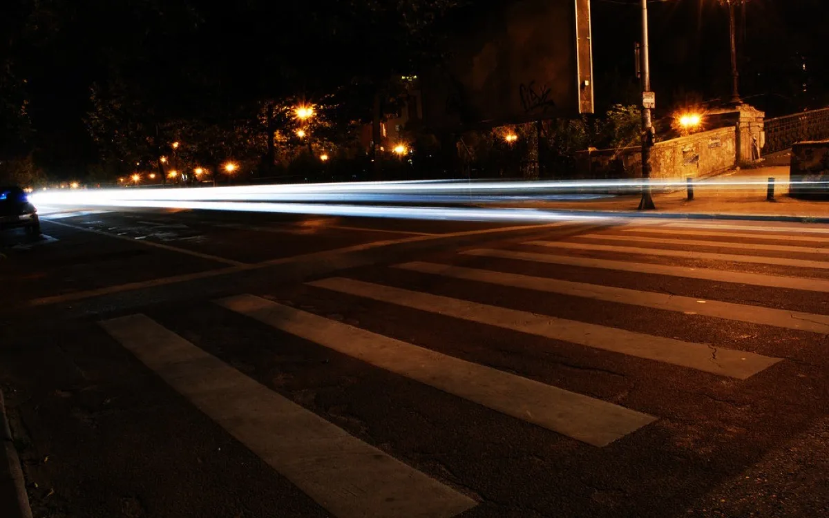 Long-exposure light trails streaking across a road at night