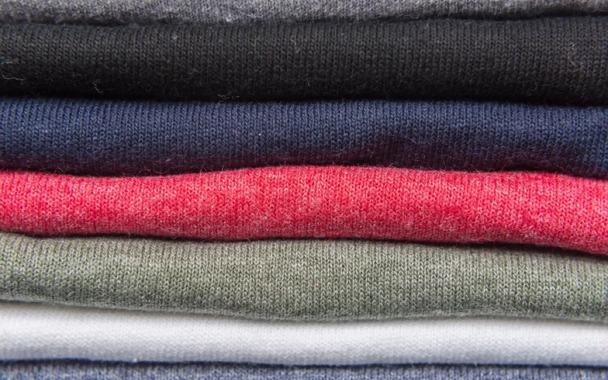 A neat stack of folded knitwear in red, navy, grey and cream