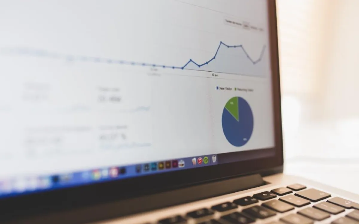 A laptop showing a web analytics dashboard with a flat traffic line and a pie chart