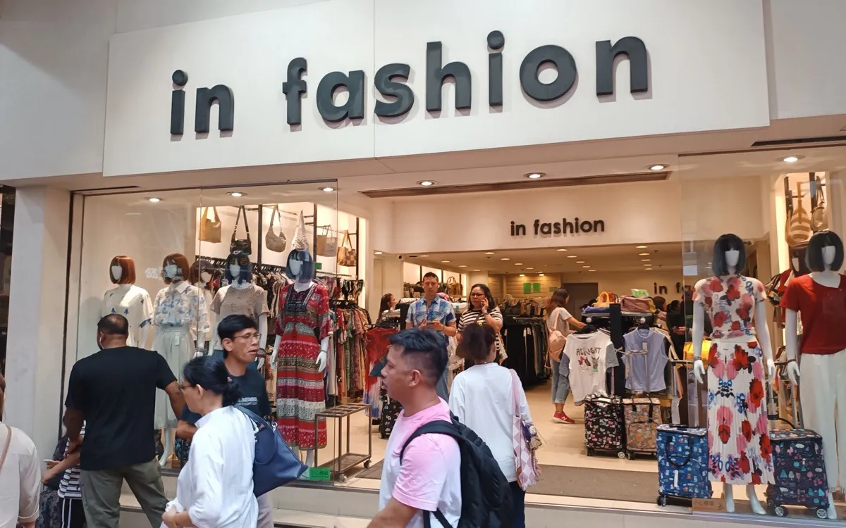 Shoppers outside the lit window of a high-street fashion store